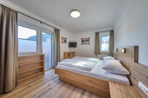 a bedroom with a large bed and a large window at Ski & Bike Appartements Forsthaus in Saalbach Hinterglemm