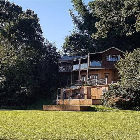 a large house sitting on top of a lush green field at Bellingen Riverside Cottages in Bellingen