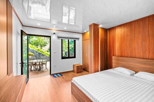 een slaapkamer met een bed en een balkon met een tafel bij Hoa An Viên Villa Hòa Bình in Lương Sơn