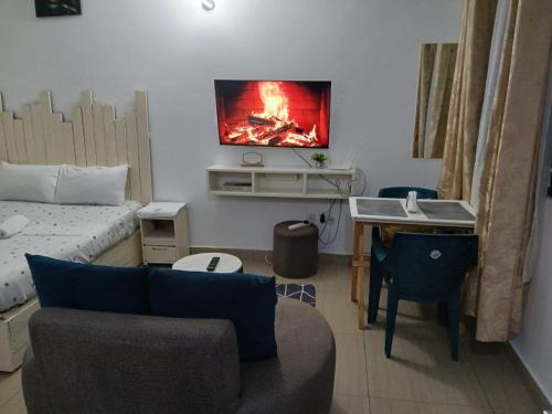 Mash Studio Apartment in Bamburi في مومباسا: غرفة معيشة مع أريكة وتلفزيون على الحائط