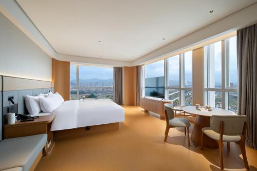 a hotel room with a bed and a table and chairs at JI Hotel Hangzhou Xiaoshan Chaoyang Subway Station in Hangzhou