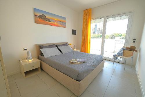 Bilocale in Residence Piazza Brescia في ليدو دي يسولو: غرفة نوم بها سرير ونافذة كبيرة