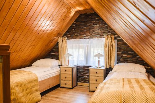 een zolderslaapkamer met twee bedden en een raam bij Agroturystyka Monte Luna in Czarnów