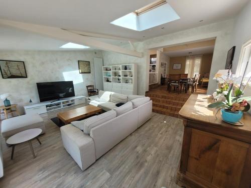 ein Wohnzimmer mit einem weißen Sofa und einem Fernseher in der Unterkunft Maison proche commerce, 20 min du Futuroscope in Vouillé