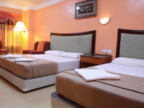 Dos camas en una habitación con paredes naranjas. en Hotel Maju, en Sitiawan