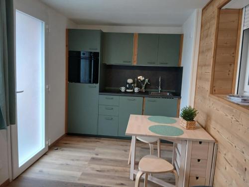 L'Amandier في Saint-Martin-sur-le-Chambre: مطبخ بخزائن خضراء وطاولة وكراسي