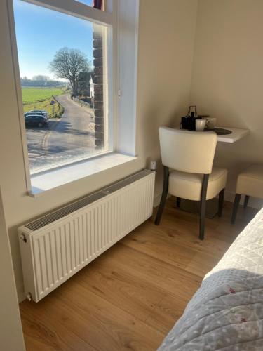 a bedroom with a window and a table and a chair at Sfeervolle kamer aan de Dorpsdijk met Gratis Ontbijt in Lobith