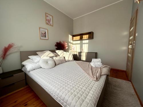 a bedroom with a large bed with white sheets and pillows at Apartament Centrum 3 pokojowy z widokiem na morze in Sarbinowo
