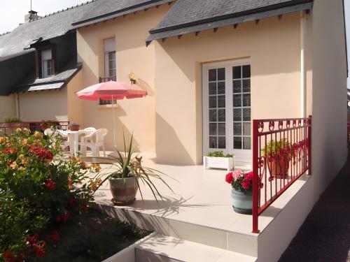 a house with a patio with an umbrella and flowers at Chambre d'hote Reine in Cancale