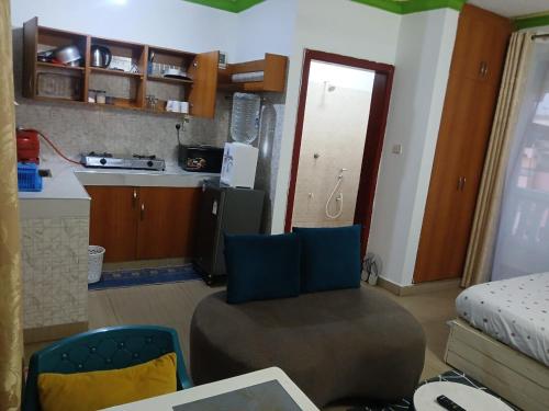 Mash Studio Apartment in Bamburi في مومباسا: غرفة معيشة مع كرسي ومطبخ