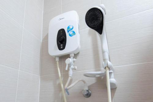 Un dispositivo eléctrico blanco en una pared de un baño. en Hotel Maju, en Sitiawan