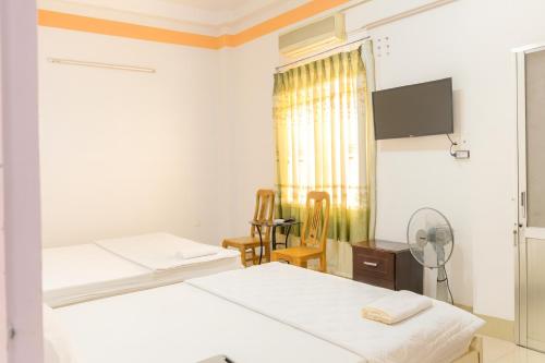 two beds in a room with a window and a fan at Nam Dương 3 Hotel in Phan Rang