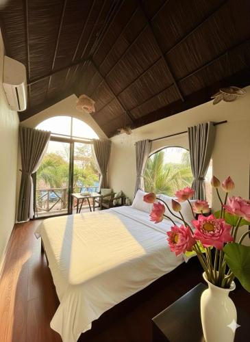 a bedroom with a large bed with a vase of flowers at Sora Traditional Homestay in Ninh Binh
