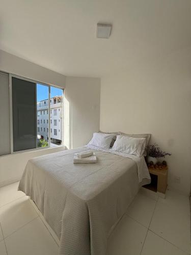 a white bed in a white room with a window at Casa Da Praia Apart Hotel in Florianópolis