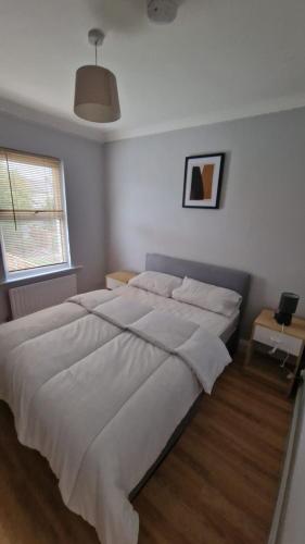 a large white bed in a bedroom with a window at Dartford Haven in Dartford