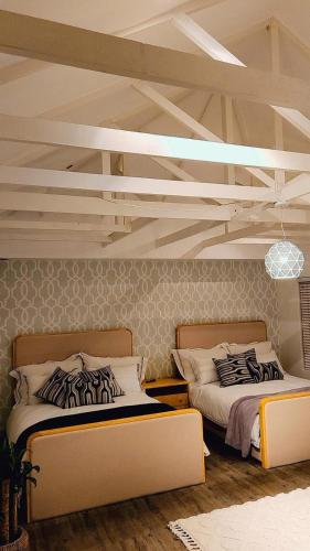twee bedden in een kamer met een plafond bij Seaside Luxe Blouberg Mansion in Cape Town