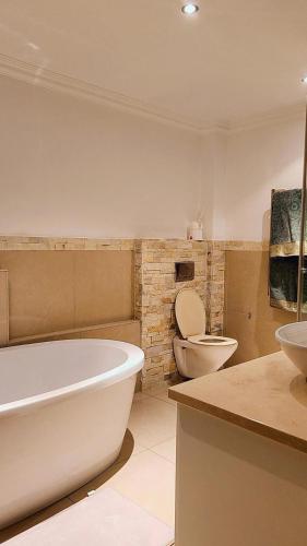 een badkamer met een bad, een toilet en een wastafel bij Seaside Luxe Blouberg Mansion in Cape Town