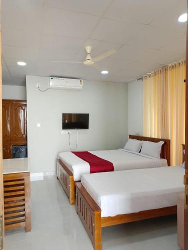 a hotel room with two beds and a tv at Casa Resort in Payyannūr