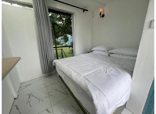 a white bed in a room with a window at OYO 91261 Thebukit, Langkawi in Kuah