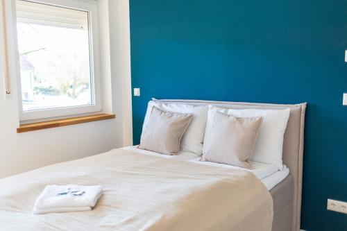 Best Stay Rhöner Gemütlichkeit Dietershausen في كنوزيل: سرير ابيض بجدار ازرق ونافذة