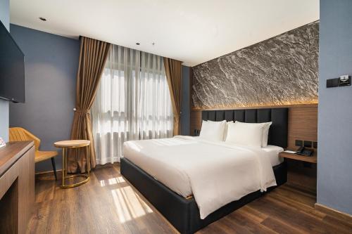 a hotel room with a large bed and a table at Nicecy Hotel Suites & Spa in Ho Chi Minh City