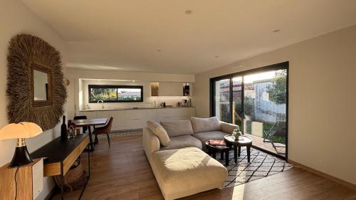 een woonkamer met een bank en een tafel bij Chambres dans la Villa Larros in Gujan-Mestras