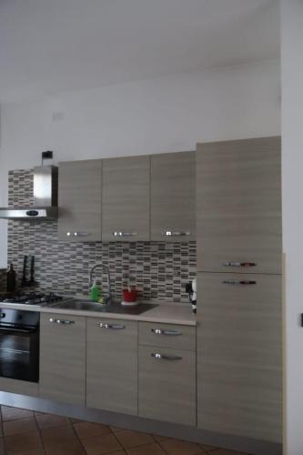 Una cocina con gabinetes blancos y una estufa. en Nottetempo, en Desio