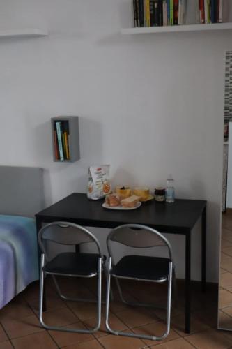 un tavolo nero con due sedie e un piatto di cibo di Nottetempo a Desio