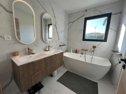 een badkamer met een bad, een wastafel en 2 spiegels bij Chambres dans la Villa Larros in Gujan-Mestras