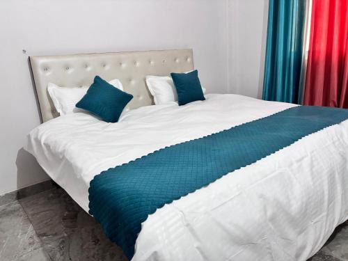 a large white bed with blue pillows on it at R D Palace and Resort in Bhauli