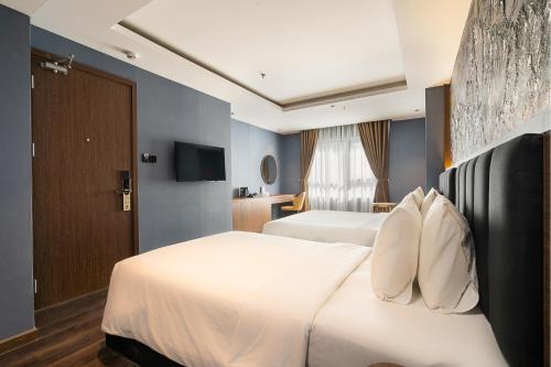 a hotel room with two beds and a television at Nicecy Hotel Suites & Spa in Ho Chi Minh City