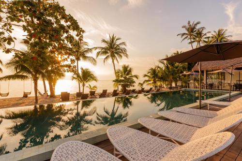 a resort swimming pool with chairs and the ocean at Samaraya Wellness Resort - Adults Only in Nathon Bay