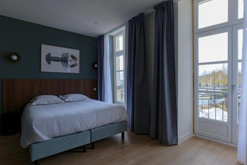 Un dormitorio con una cama y una ventana grande. en Hôtel l'Hermine - Vannes Port de plaisance, en Vannes