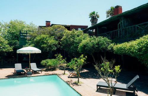 Posada Paradiso في خوسيه اجناسيو: حمام سباحة مع كرسيين ومظلة