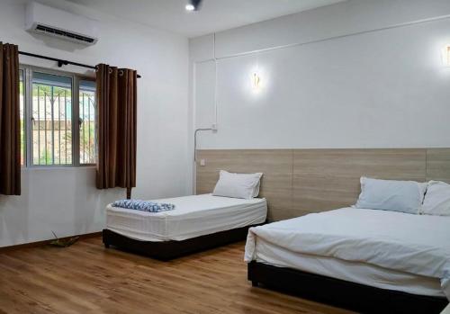 a bedroom with two beds and a window at Grace Homestay Taiping in Taiping