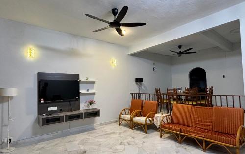 a living room with a flat screen tv and chairs at Grace Homestay Taiping in Taiping