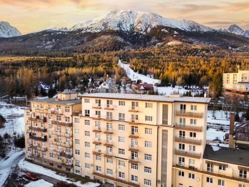 an apartment building with mountains in the background at TATRYSTAY Apartmán v srdci Tatier in Smokovce
