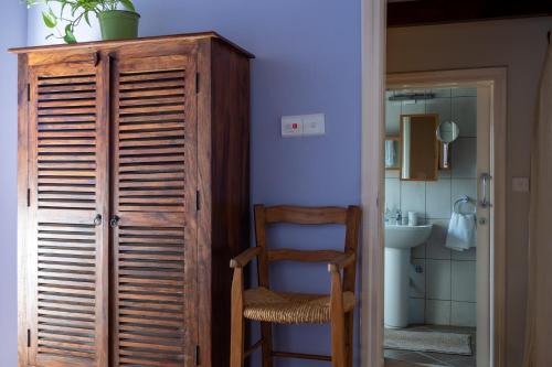 a bathroom with a wooden cabinet and a chair at Villa Monti Cozy Yard & BBQ Perfect for Families & Friends in Kato Lefkara