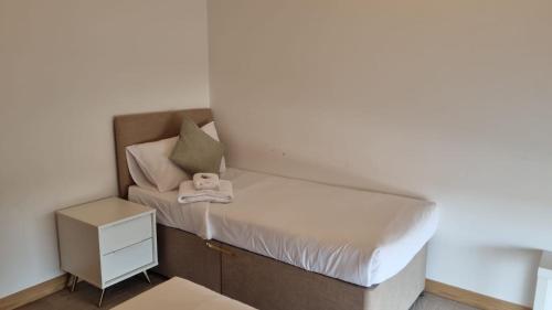 a small bedroom with a bed and a nightstand at Modern 2 bed flat with balcony in Southend-on-Sea