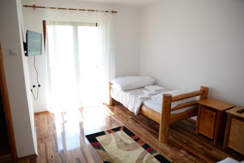a small bedroom with a bed and a window at Motel Nacionalni Restoran Ognjiste in Koruge