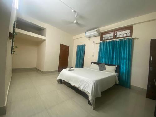 Hotel O Eco guest house في Gauhāti: غرفة نوم بسرير ابيض وستائر زرقاء