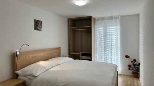 a bedroom with a white bed and a window at The Golf apartments in Interlaken