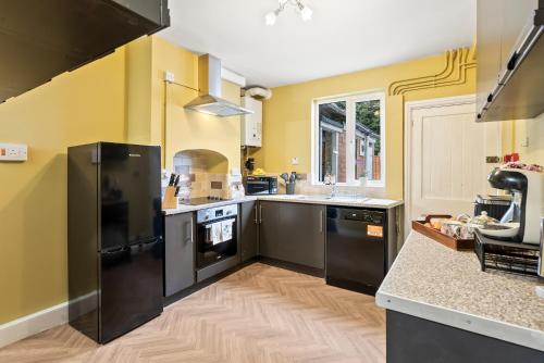 a kitchen with black appliances and yellow walls at Victorian 5-Bed Home, Loft, Walk to City & Cricket in Worcester