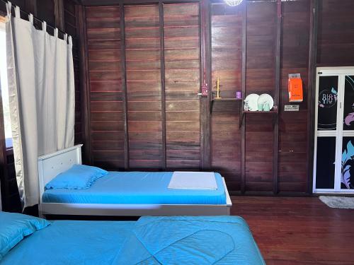 a bedroom with two beds and a wooden wall at Hotel O Sri Ayu Inn in Kampung Gurun