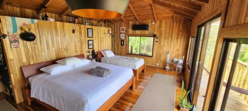 two beds in a room with wooden walls and wood floors at Teak house in a forest above the beach 