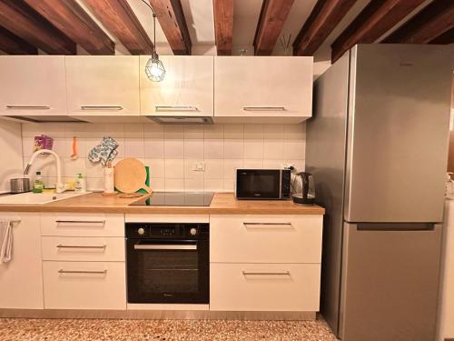 a kitchen with white cabinets and a stainless steel refrigerator at Ca' Della Torre, a 5 min da Rialto in Venice