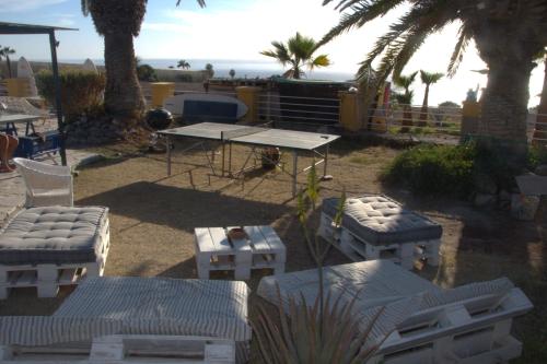 a patio with a table and chairs and palm trees at The Tree House Surf Camp in Adeje