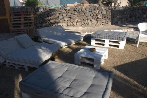 a patio with couches and tables and a stone wall at The Tree House Surf Camp in Adeje