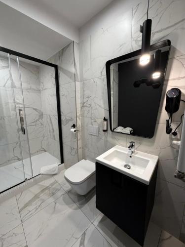 a bathroom with a sink and a toilet and a mirror at Apartamenty Prestiż Podfigórna 200 metrów od centrum in Koszalin