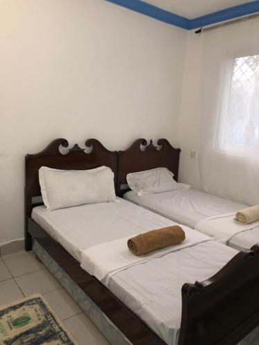 two beds in a room with white walls at Blue Waves Apartments in Mombasa